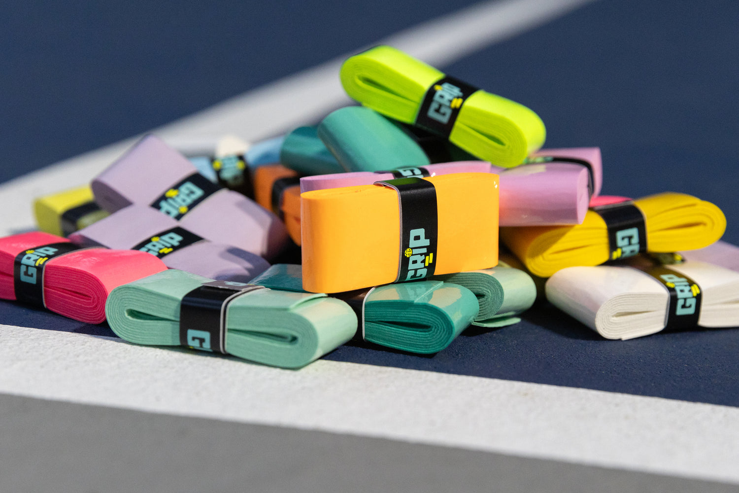 Pile of GRIP overgrips on pickleball court